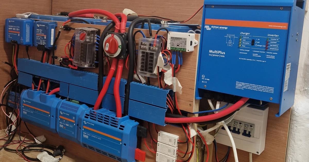 Інвертор/зарядний пристрій Victron, сонячні контролери заряду та шинопроводи, змонтовані на стіні автодому