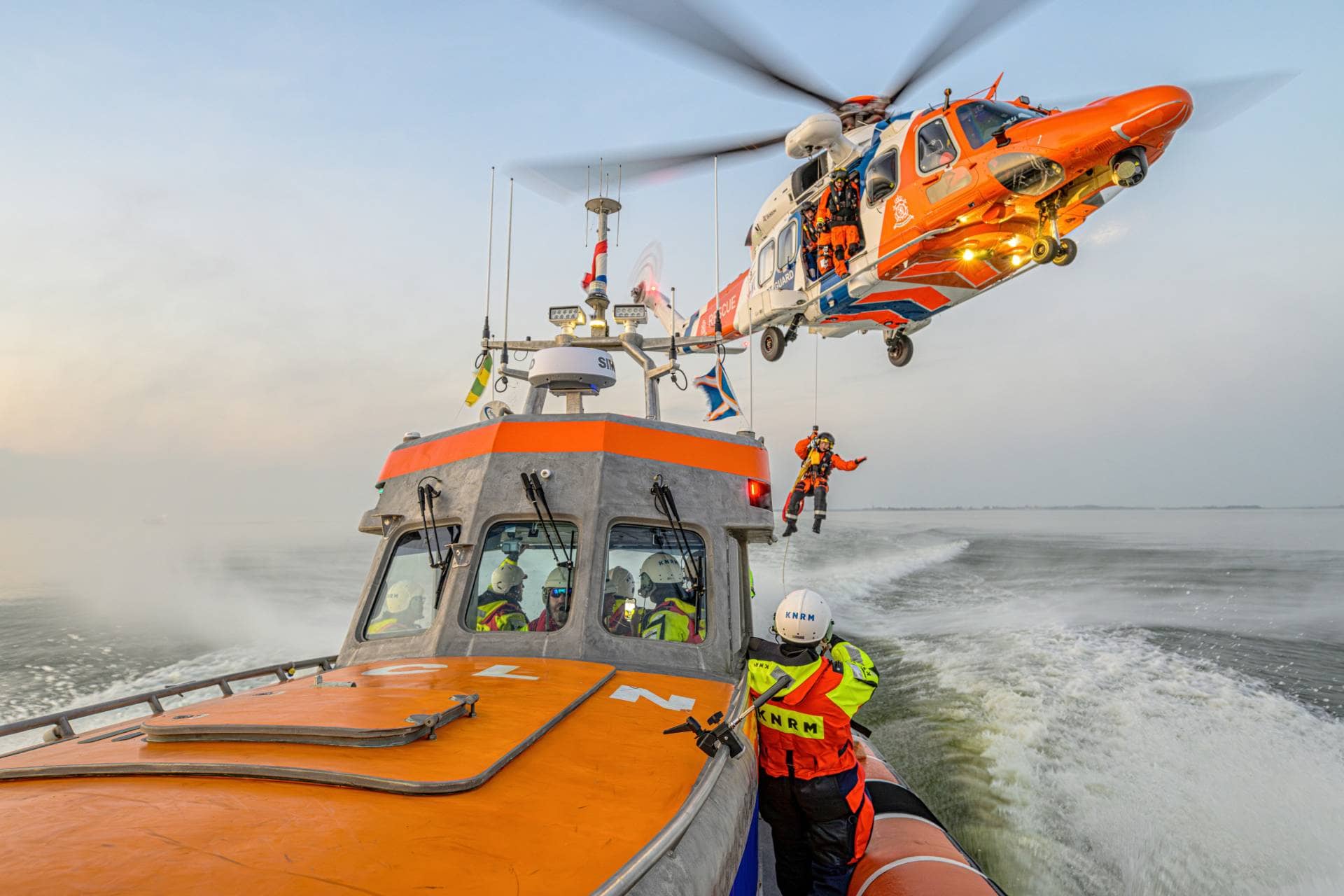 Рятувальне судно KNRM у морі з рятувальним гелікоптером, що піднімає члена екіпажу