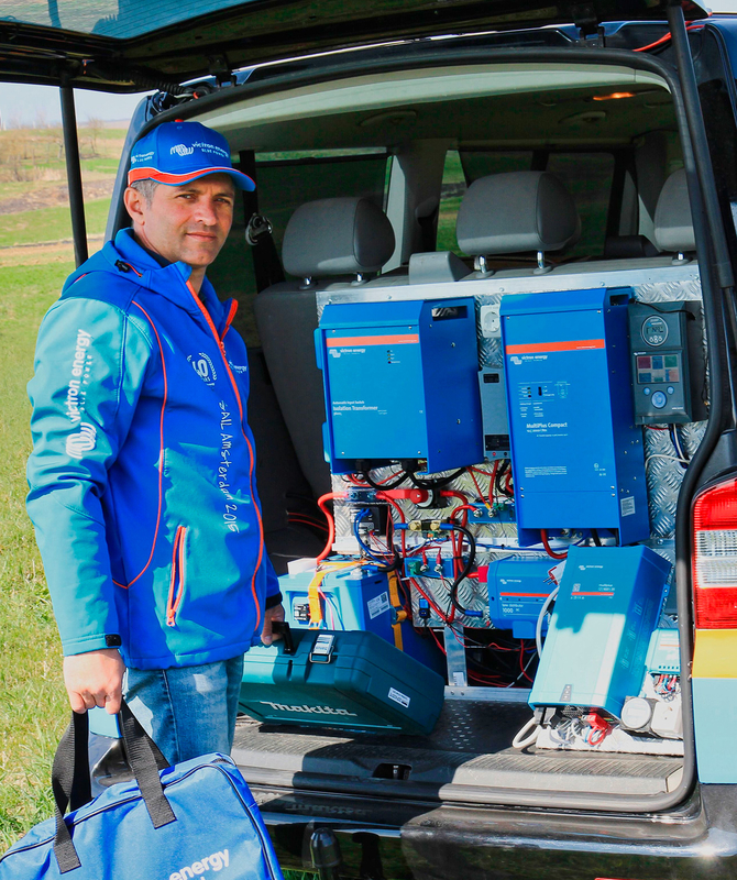 Victron professional standing next to Victron equipment in the back of a car